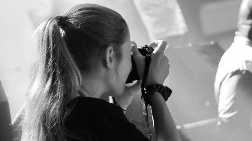 A woman takes a photograph using a camera